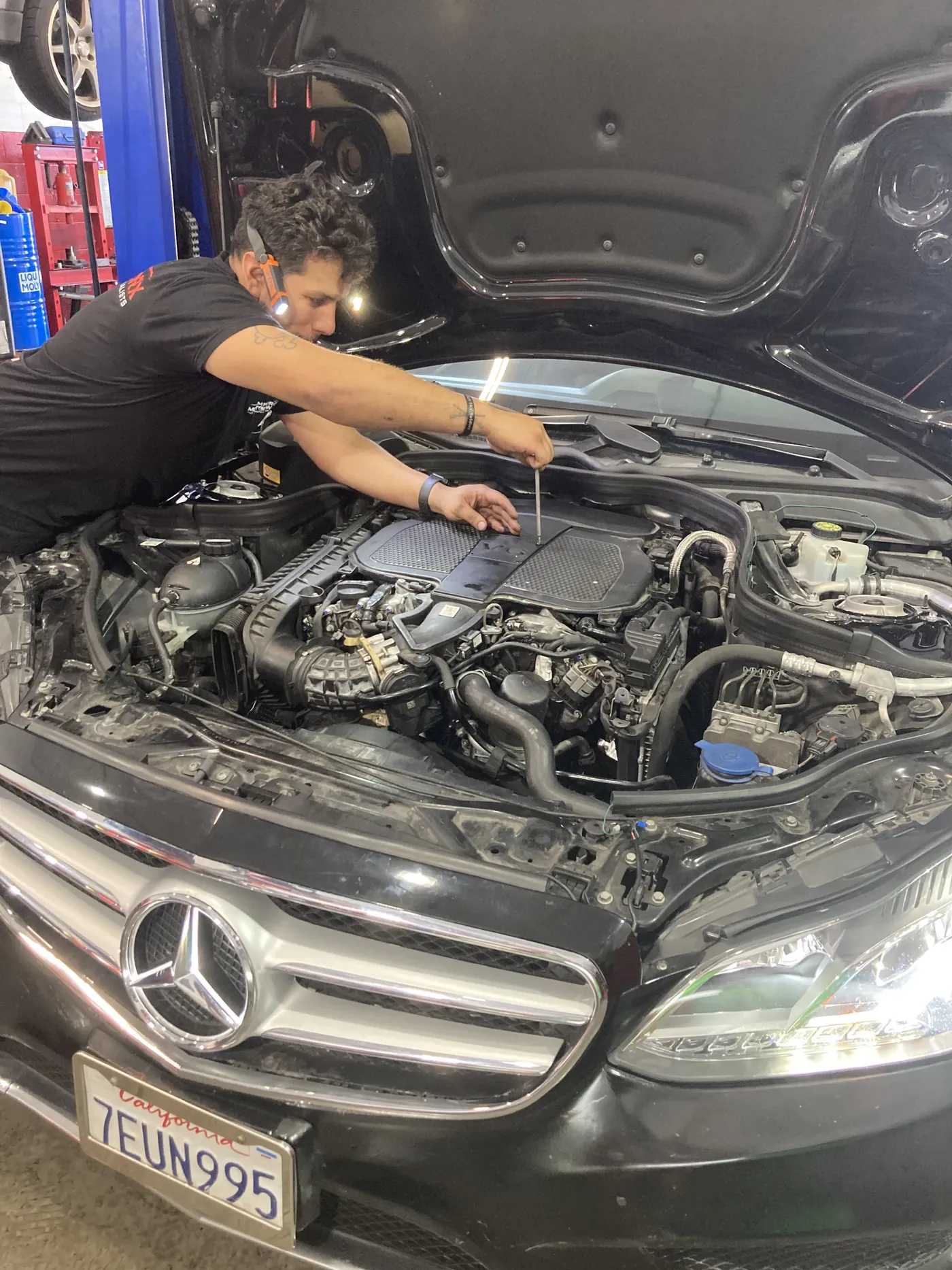 Technician working in the engine bay of a Mercedes-Benz