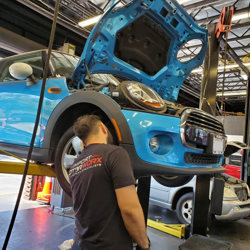 Technician servicing a MINI Cooper on the lift